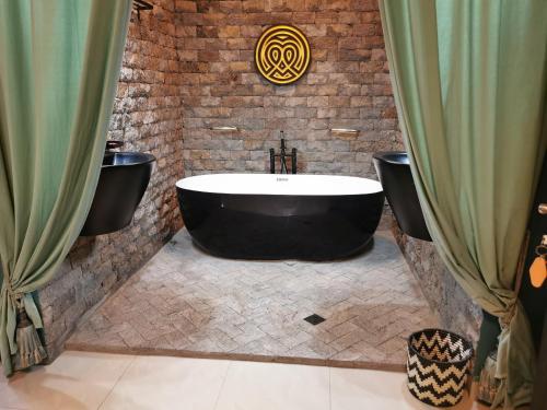 a bathroom with a black tub and a brick wall at Ibuye Villa Holiday Home in Nyakinama