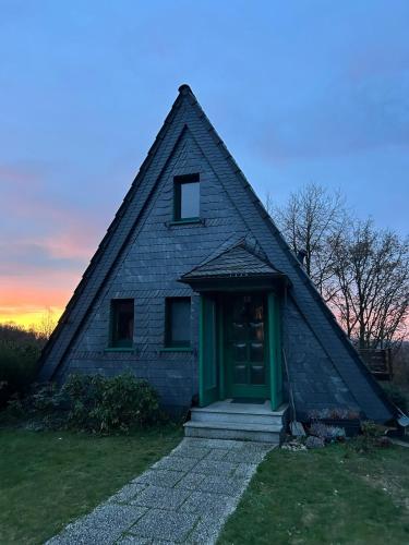 a house with a gambrel roof with a green door at Chalet am Biggesee in Olpe