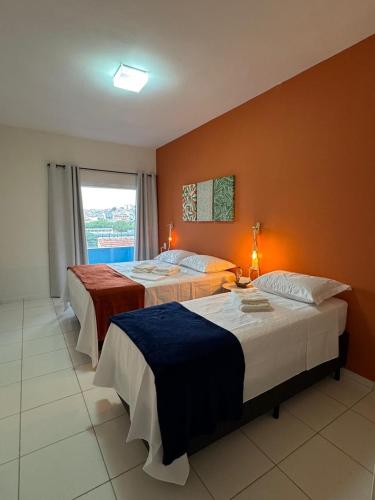 a hotel room with two beds and a window at Pousada Sete Colinas in Bragança Paulista