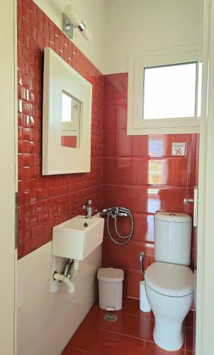 a red bathroom with a toilet and a sink at Mary's luxury apartment Nemea 1 in Neméa