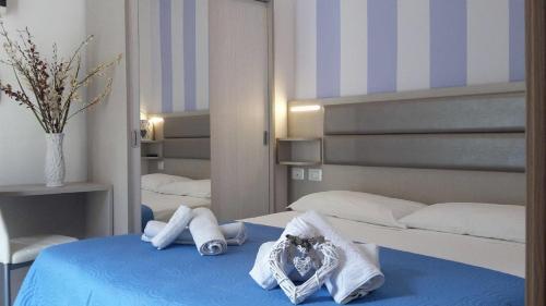 a bedroom with two beds and towels on a bed at Hotel Arno in Misano Adriatico