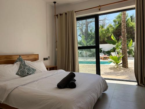 a bedroom with a bed and a large window at U Paradisu Villas-Jambiani in Kibigija
