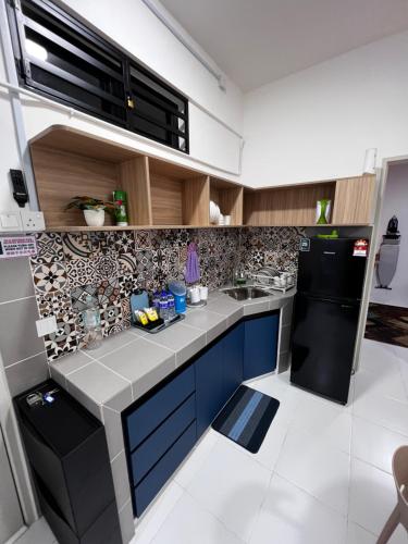 斯里伊斯兰德Homestay Kesidang的厨房配有蓝色橱柜和黑色冰箱。