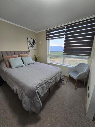 a bedroom with a bed and a chair and a window at Rancagua Lujo y comodidad Depto con Piscina y Estacionamiento in Rancagua
