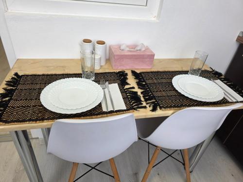a table with two white plates and a pink box at Sya House in Craiova