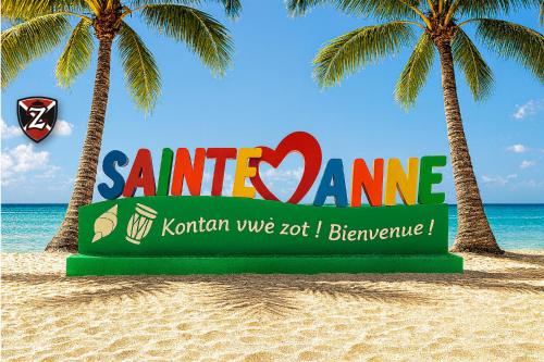 un cartello su una spiaggia con due palme di Villa Zeinga a Sainte-Anne