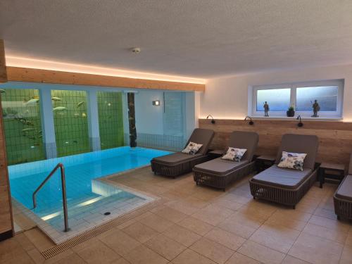 einen Pool in einem Haus mit Stühlen und einem Sofa in der Unterkunft Adler Hotel-Pension in Fulpmes