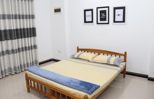 a bed in a room with two pictures on the wall at Skylar Homestay - Comfortable Room with Balcony in Panwila Kandy in Panwila