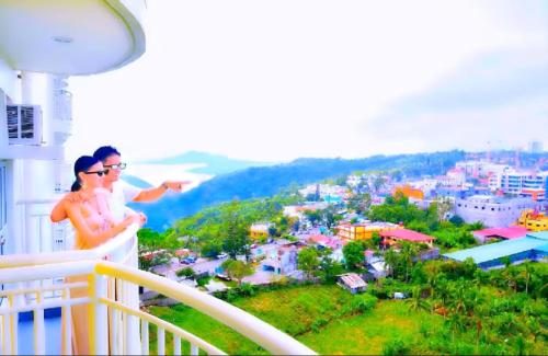 a woman standing on a balcony looking at a city at SweetLove Hideaway CITYLAND Condo 2-BR, 2-Bath, Living room, Sleeps 12, Kitchen, Free Pool, Wi-Fi, 2 Parking, View-Deck on 24F rooftop in Iruhin