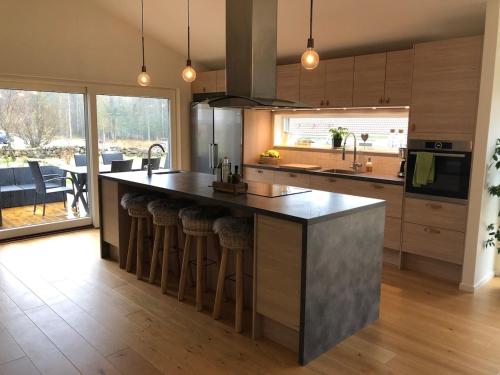 Una cocina con una gran isla con taburetes de bar. en Stunning, modern home with a lakeview, en Äspered