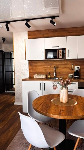 a kitchen with a wooden table and white chairs at MunSpell Apartment in Kopaonik