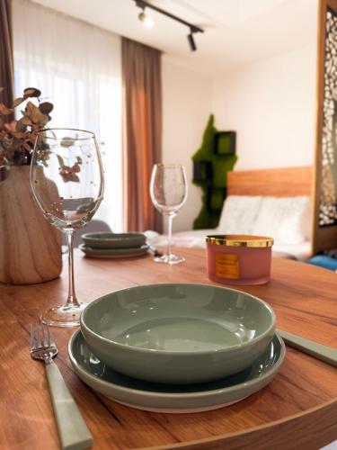 a wooden table with a plate and two wine glasses at MunSpell Apartment in Kopaonik