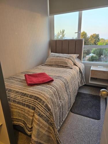 una camera da letto con un letto e un asciugamano rosso sopra di Confortable Departamento Familiar 3 Dormitorios a Rancagua