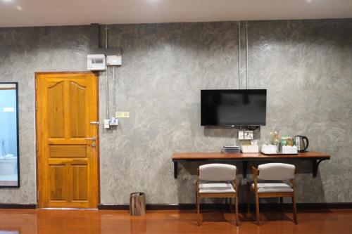 a table with two chairs and a television on a wall at Momento House in Phra Nakhon Si Ayutthaya