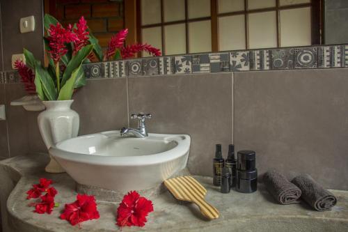 a bathroom sink with red flowers and a vase at Yacumaman Sanctuary in Tarapoto