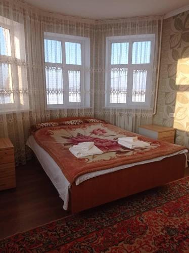 ein Schlafzimmer mit einem großen Bett mit Fenstern und einem Teppich in der Unterkunft Гостевой дом Маман in Maman