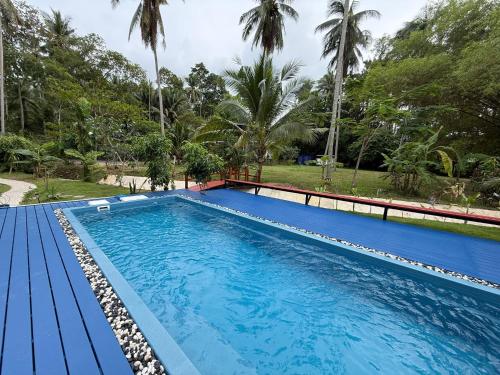 a large blue swimming pool with trees in the background at Samui Land Haven in Amphoe Koh Samui
