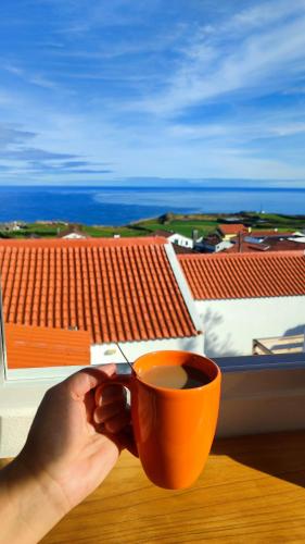 a person holding a cup of coffee on a table at Azure Vista Lodge in Nordeste