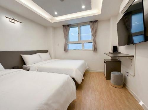a hotel room with two beds and a television at Hotel CF in Seoul