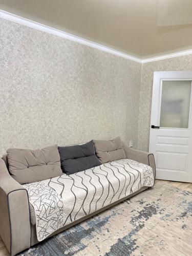 un divano in una stanza con un muro di Квартира в Центре Шымкента Плаза a Shymkent