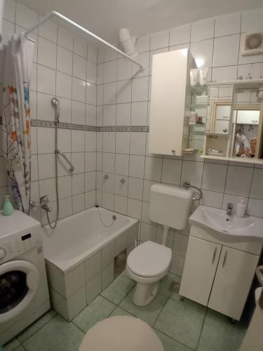 a white bathroom with a toilet and a sink at Apartman BRKO in Bihać