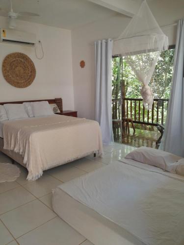 a bedroom with two beds and a balcony at Casa hibiscus in Itacaré