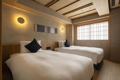 duas camas em um quarto com duas janelas em soyo-ne kyoto sanjo em Quioto