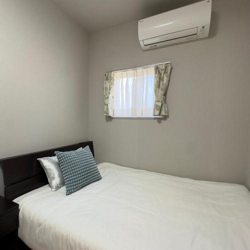 a bedroom with a white bed and a air conditioner at 久松の宿 in Miyako-jima