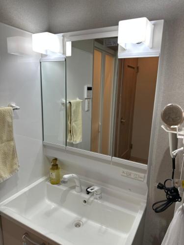a bathroom with a sink and a large mirror at 久松の宿 in Miyako-jima