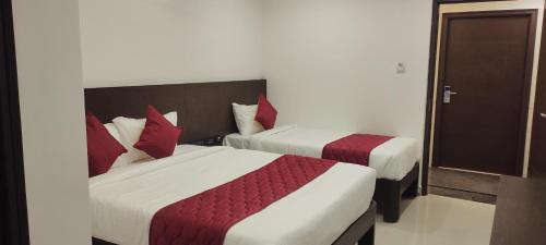 two beds in a hotel room with red pillows at Hotel Orion Inn in Tirupati