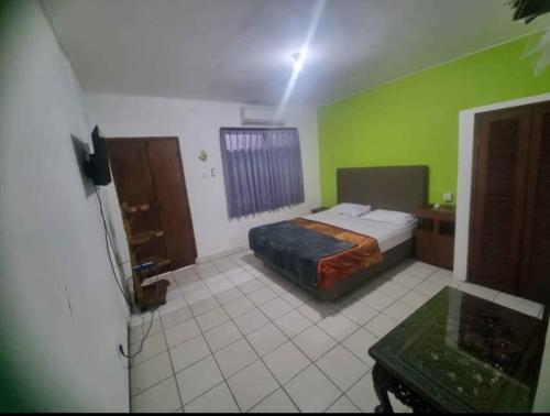 Un dormitorio con una cama y una pared verde. en Mulia Legian guest house, en Seminyak