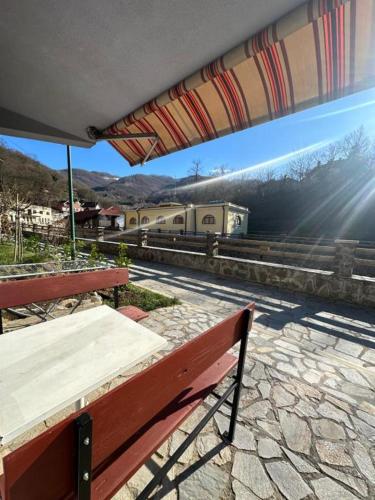 a bench with a table and an umbrella at Studio - Apartmani 3 in Jošanička Banja