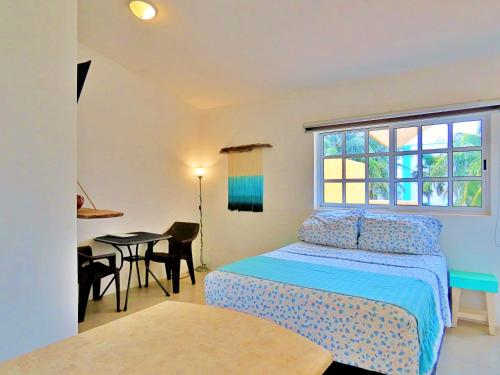 a bedroom with a bed and a table and a window at Casa Brisamar , Studios in Puerto Morelos