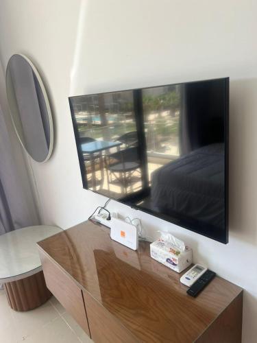 a tv on a wall with a bed and a table at Serenity Studio in G-Cribs in El Gouna