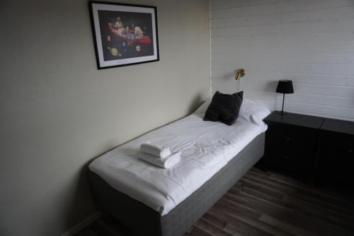 - un petit lit avec des draps blancs et des oreillers dans l'établissement Vannebodagatan, à Frövi