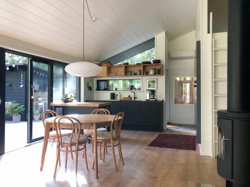 a kitchen and dining room with a table and chairs at Elegant New Cottage On Quiet Woodland Site in Nykøbing Sjælland