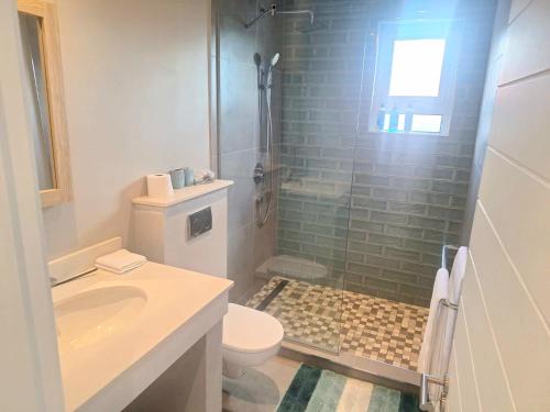a bathroom with a shower and a toilet and a sink at Sunset Corner in Rivière Noire