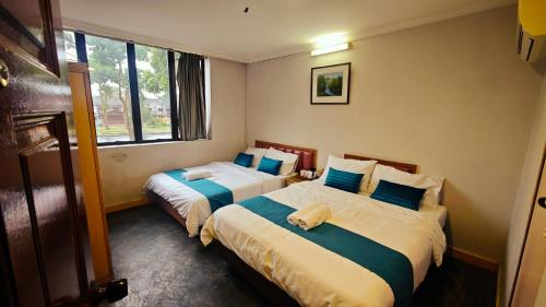 una habitación con dos camas en una habitación con ventanas en Wangsa Village Inn, en Ulu Tiram