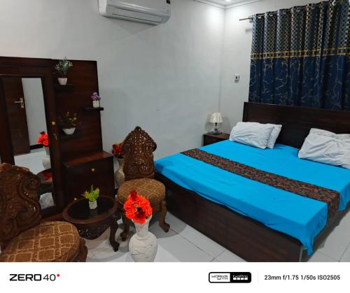 a bedroom with a blue bed and two chairs at Ryazm Guest house in Rawalpindi