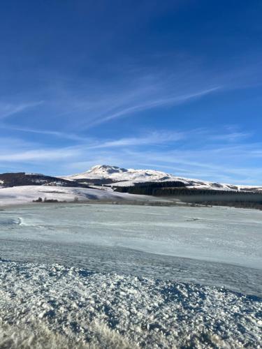 un bacino d’acqua con montagne innevate sullo sfondo di Appartement Dans un village en Auvergne sancy a Égliseneuve-dʼEntraigues