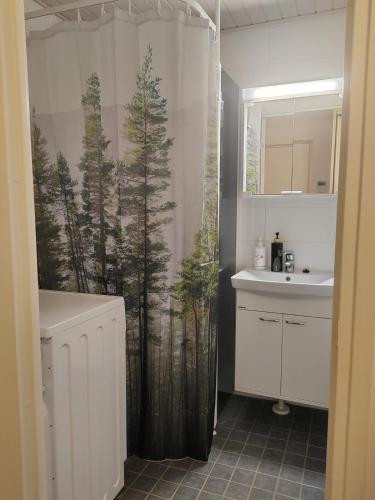 a bathroom with a shower curtain with trees on it at Pikku-Kassu in Hämeenlinna