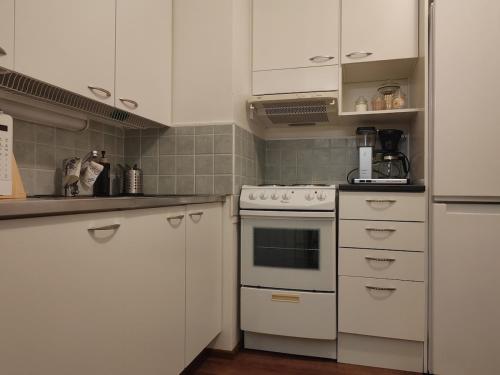 una cucina con mobili bianchi e una stufa di Pikku-Kassu a Hämeenlinna