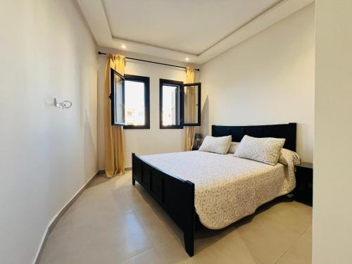 a bedroom with a bed and two windows at Colina Smir par Immo Marina Vacances de Rêve B1-10 in Oulad Akkou