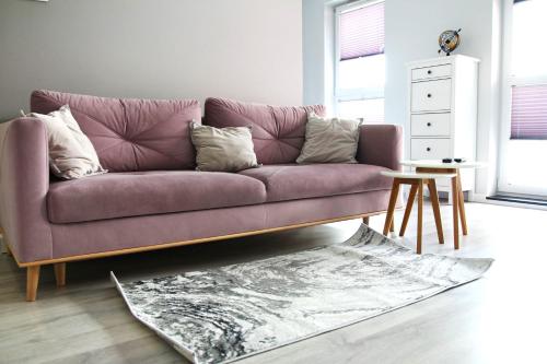 ein lila Sofa im Wohnzimmer mit einem Tisch in der Unterkunft APARTAMENT TETRIS - CENTRUM in Kielce