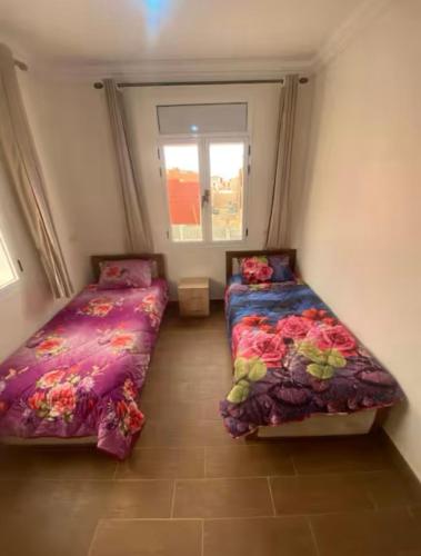 a room with two beds and a window at Immeuble Elmo plage Mirleft in Mirleft