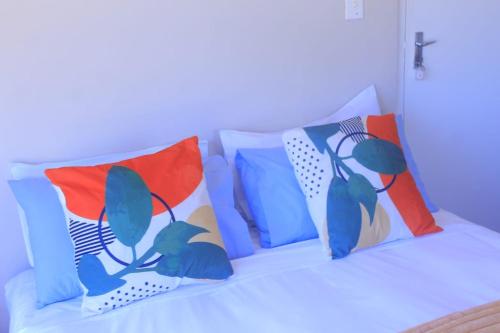 uma cama branca com almofadas coloridas em Oasis em Glencairn