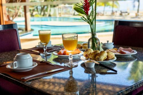 a table with food and drinks next to a pool at Hotel Karapitangui in Morro de São Paulo