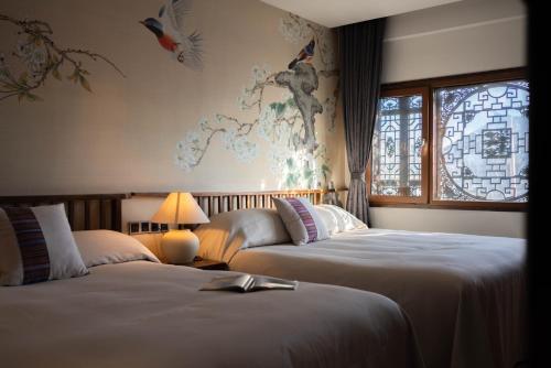 2 camas en una habitación de hotel con un mapa en la pared en Lijiang Ancient Town Landscape Garden Hotel 山水爱斯花园酒店, en Lijiang