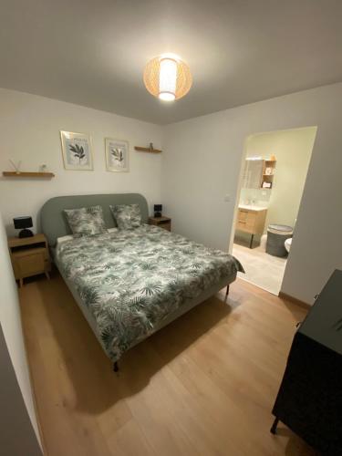 a bedroom with a bed with a green comforter at COSY Dépendance proche Saint- Émilion in Le Fieu