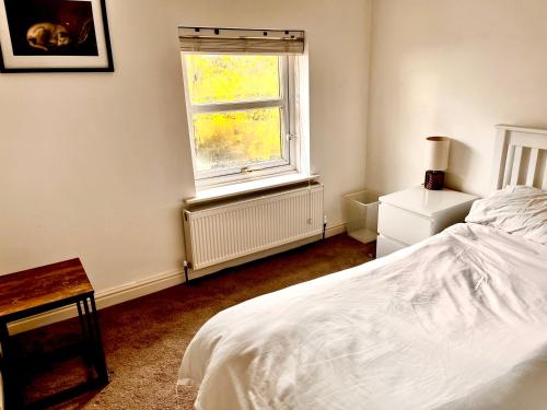 特伦特河畔斯托克Squirrel Cottage的一间卧室，有一张白色的床和一扇窗户